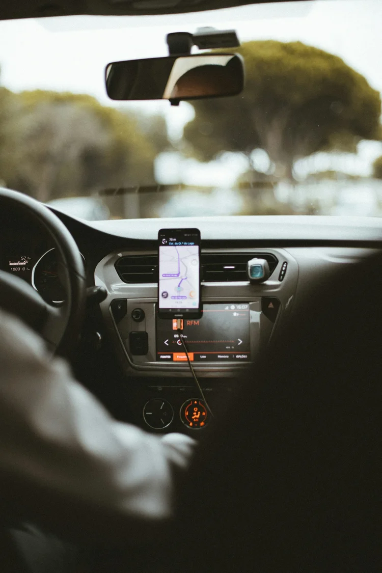 Inside view of a car dashboard showing a GPS device and a radio, with trees outside the windshield.